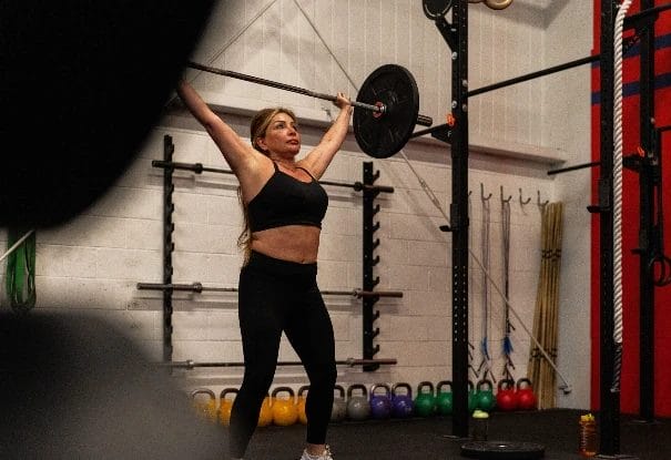 Athlete performing barbell overhead lift inside gym at CrossFit Plainfield