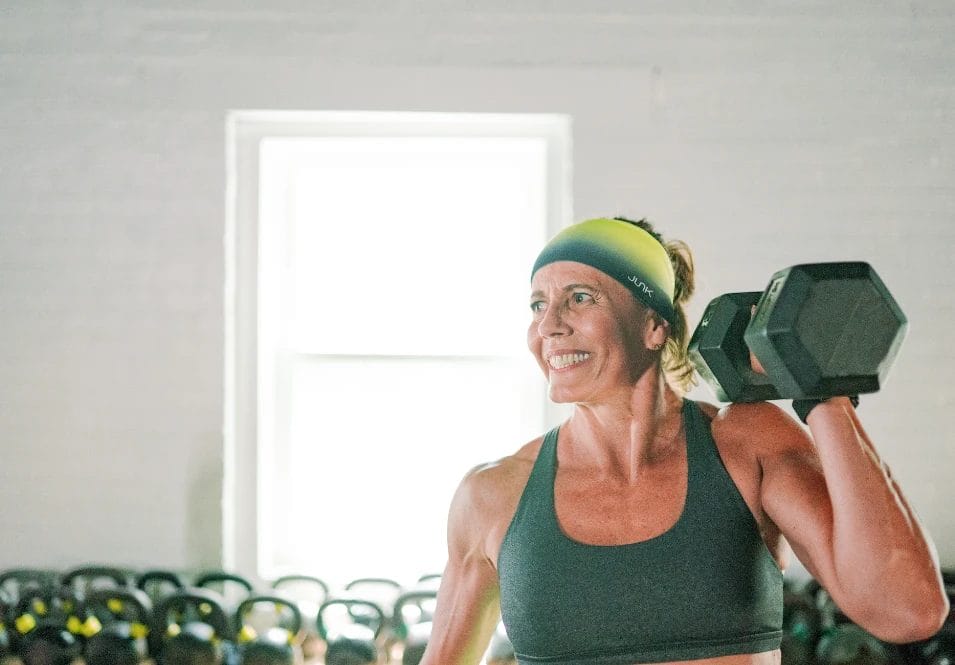 Woman lifting dumbbell for shoulder press workout at CrossFit Plainfield